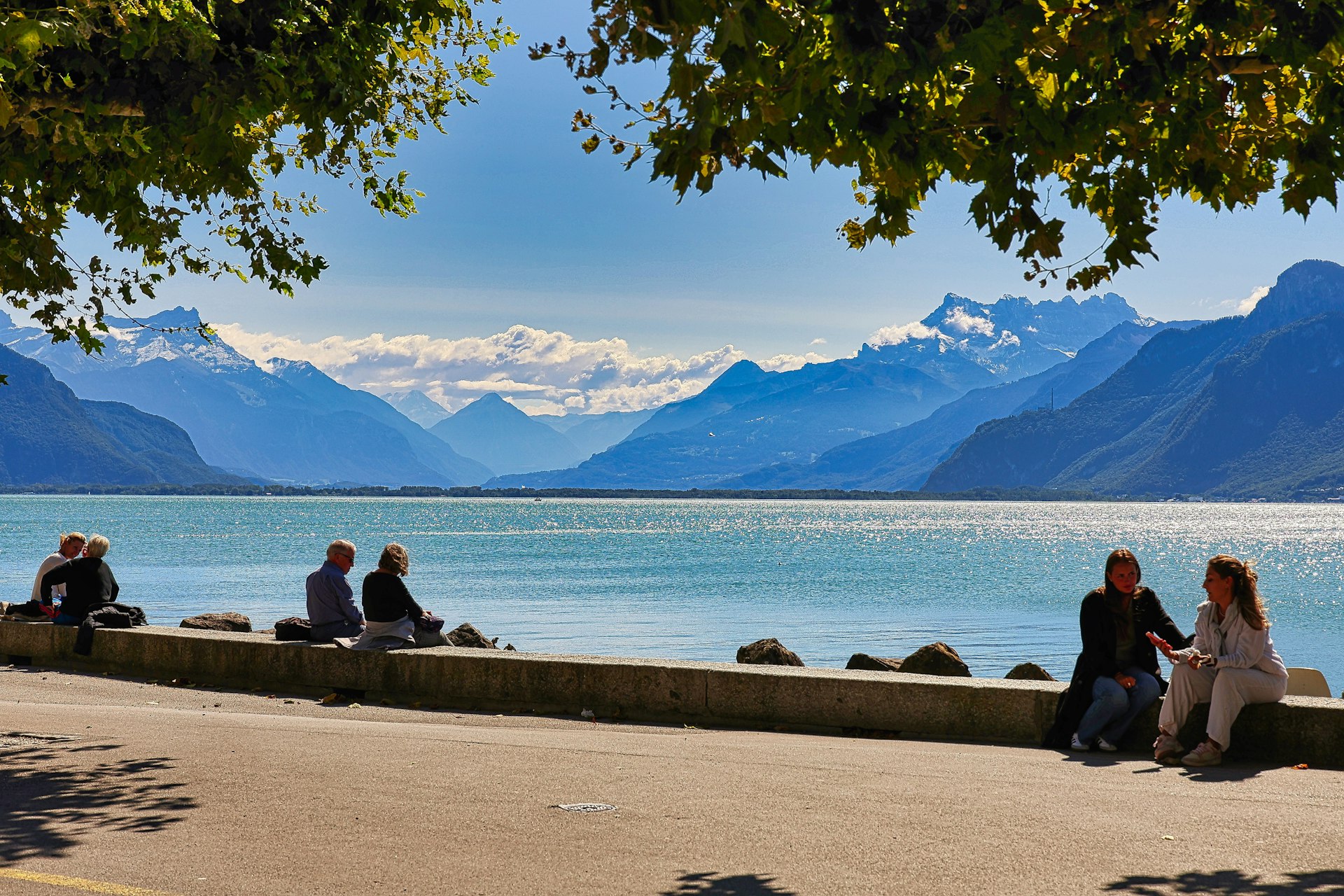 A group of people sitting on the side of a lake